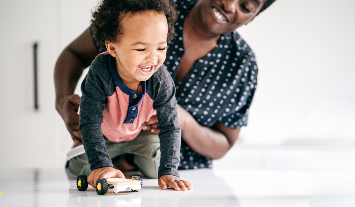 small child holding a toy car with their smiling parent