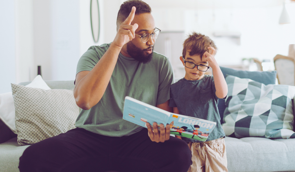 male teacher studying a book with hard of hearing student