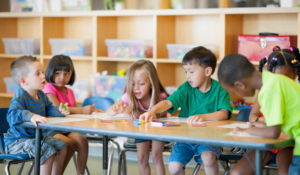 preschoolers sharing crayons at a table