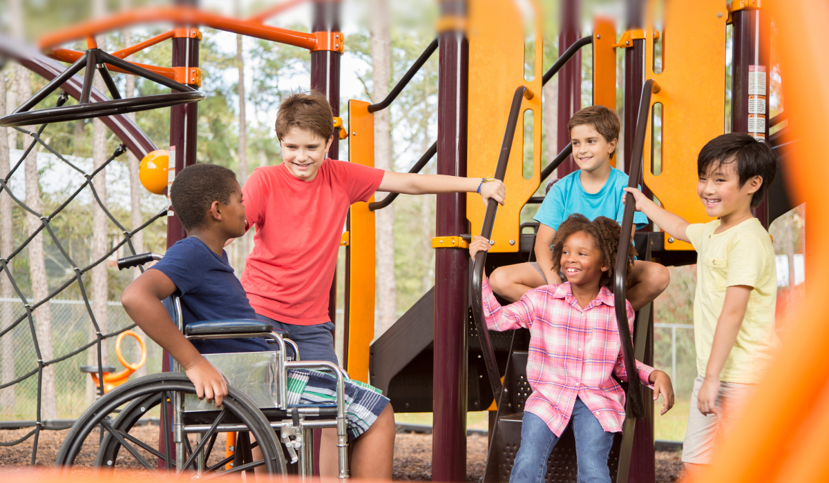 group of students on the playground, one of which is in a wheelchair