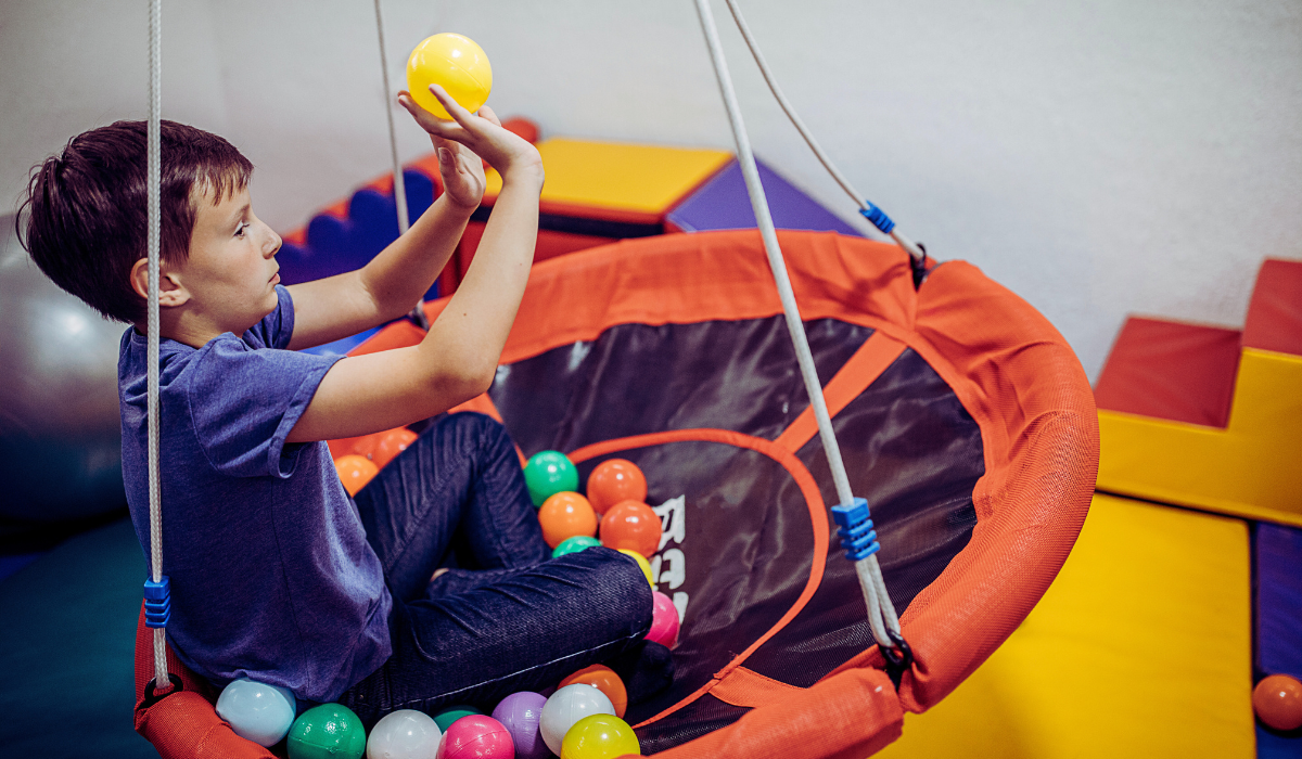 child on a therapy swing with a ball