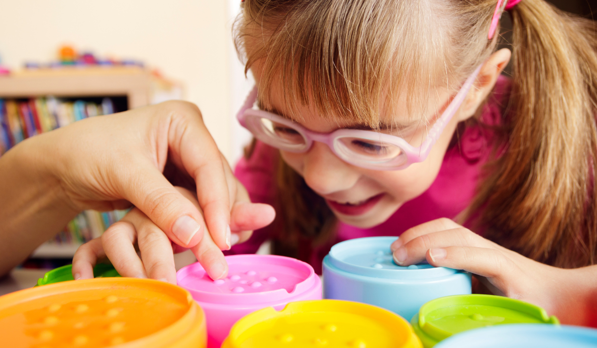 girl with glasses and colorful tactile cups